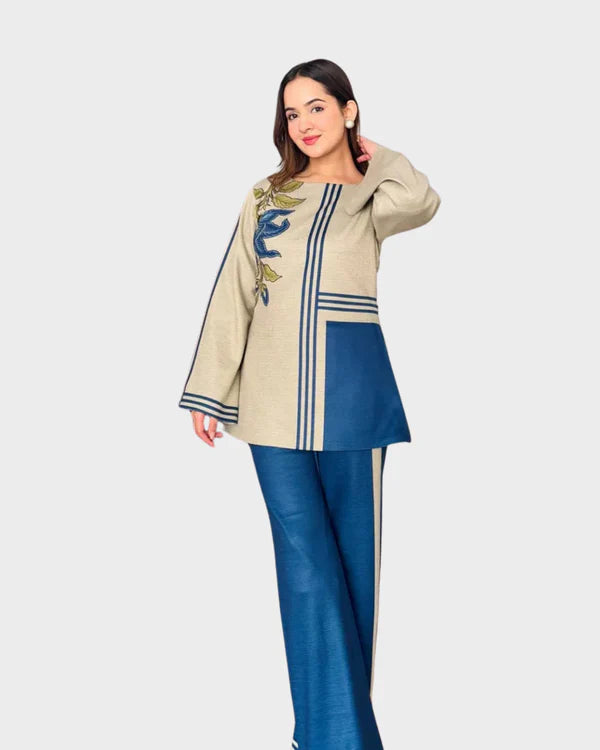 Woman wearing a cream top with blue accents and matching pants on a white background