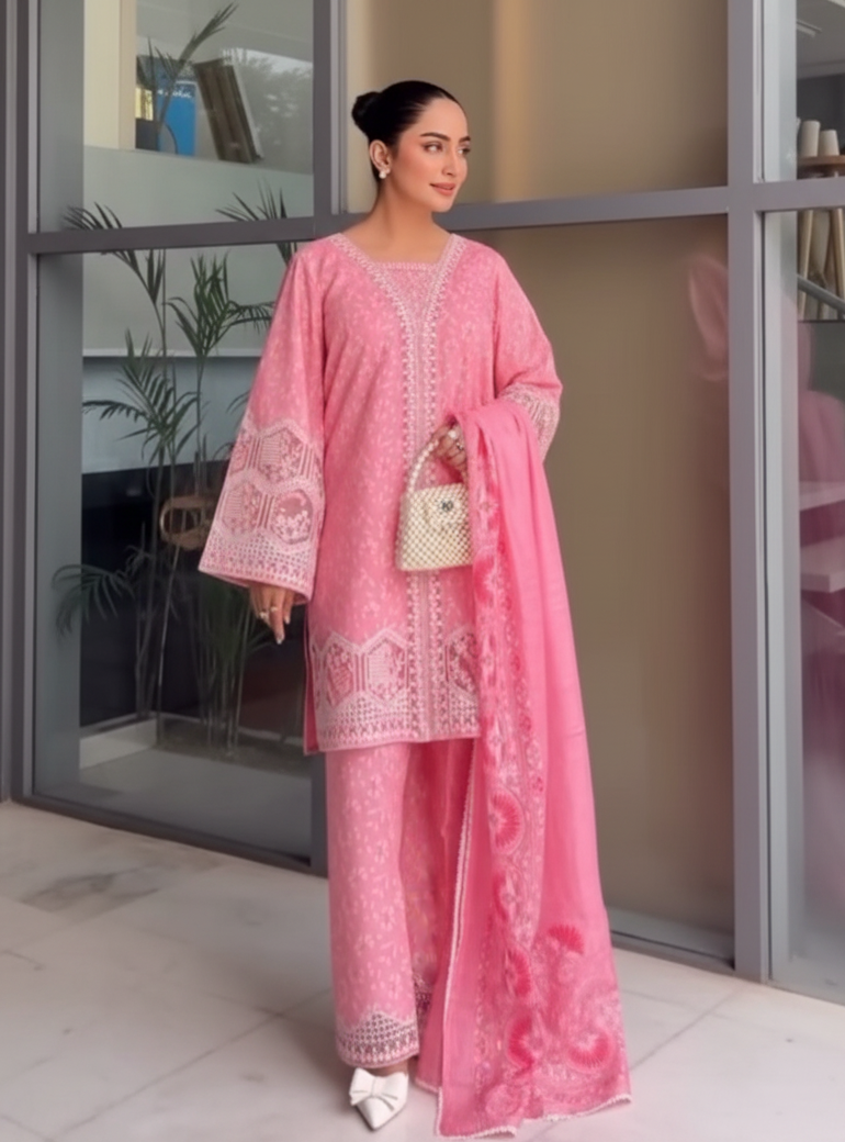 Woman in a pink traditional outfit standing indoors with a neutral background