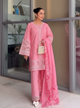 Woman in a pink traditional outfit standing indoors with a neutral background
