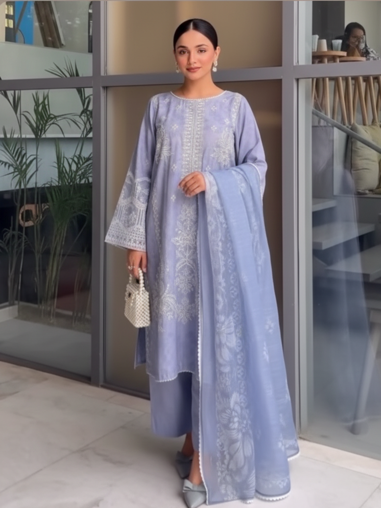 Woman in a light blue embroidered dress standing indoors.