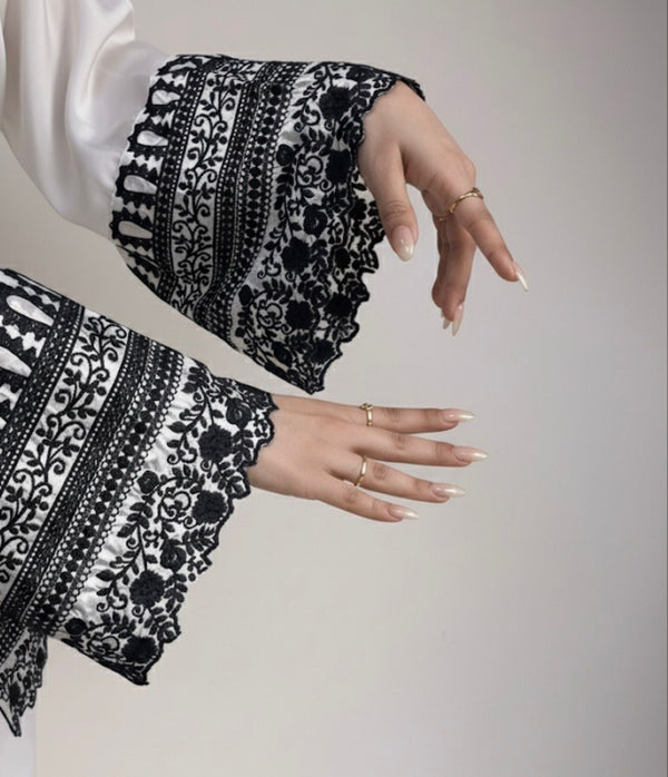 Close-up of hands wearing black and white patterned gloves on a plain background