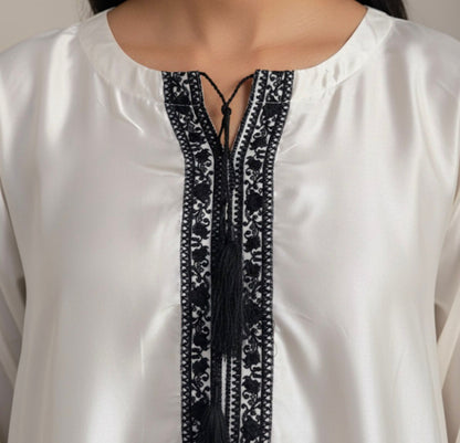 White blouse with black embroidery details on a neutral background
