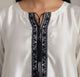 White blouse with black embroidery details on a neutral background