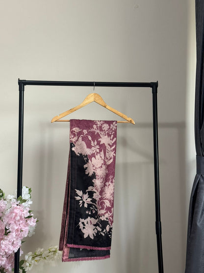 Decorative scarf with floral pattern hanging on a rack against a neutral wall.