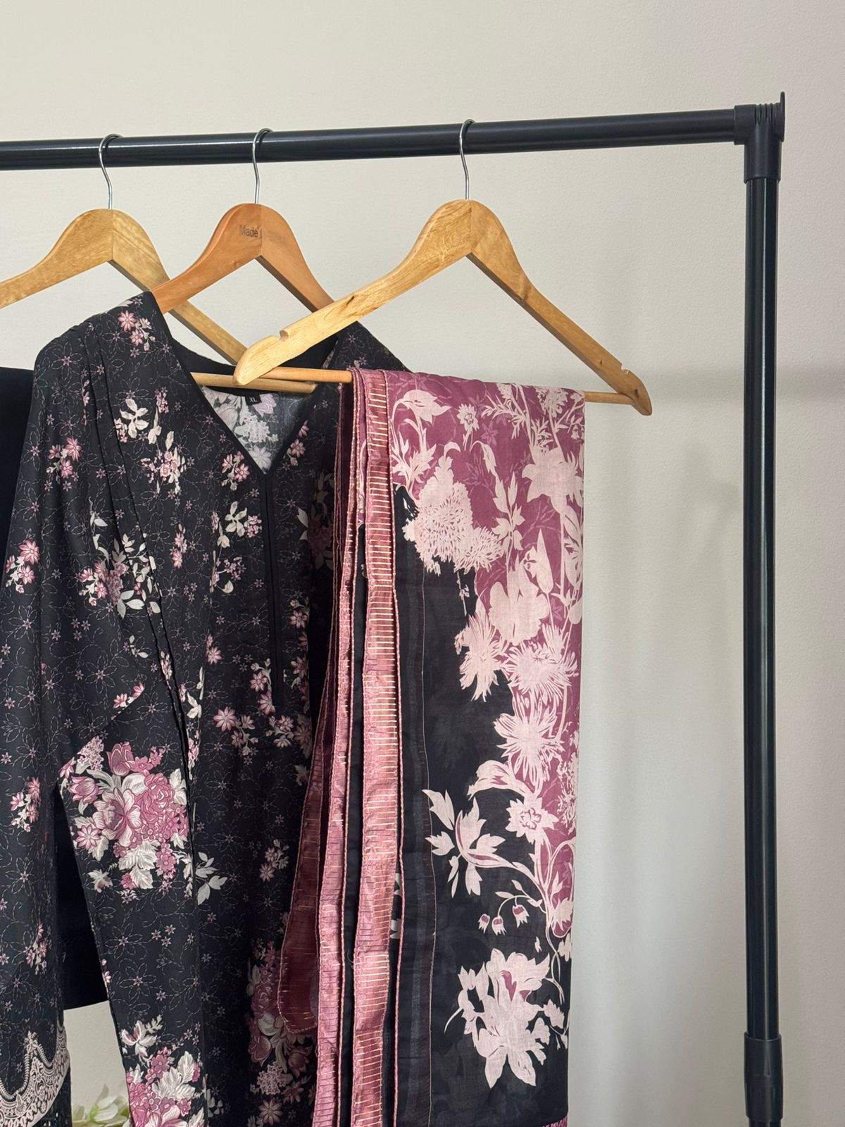 Floral-patterned scarves on a rack against a plain background