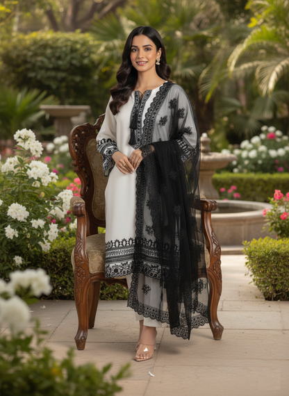 Woman in a black and white traditional outfit sitting on a wooden chair in a garden setting.