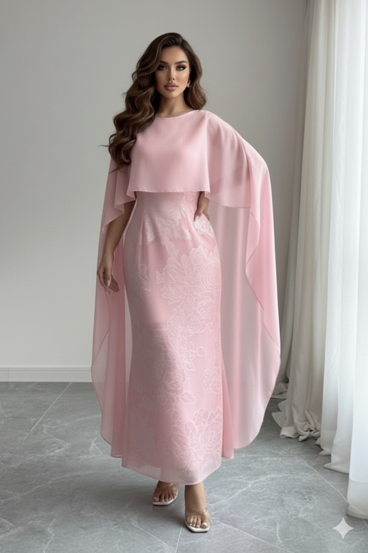 Woman wearing a pink dress with a cape in a room with gray flooring and white curtains.