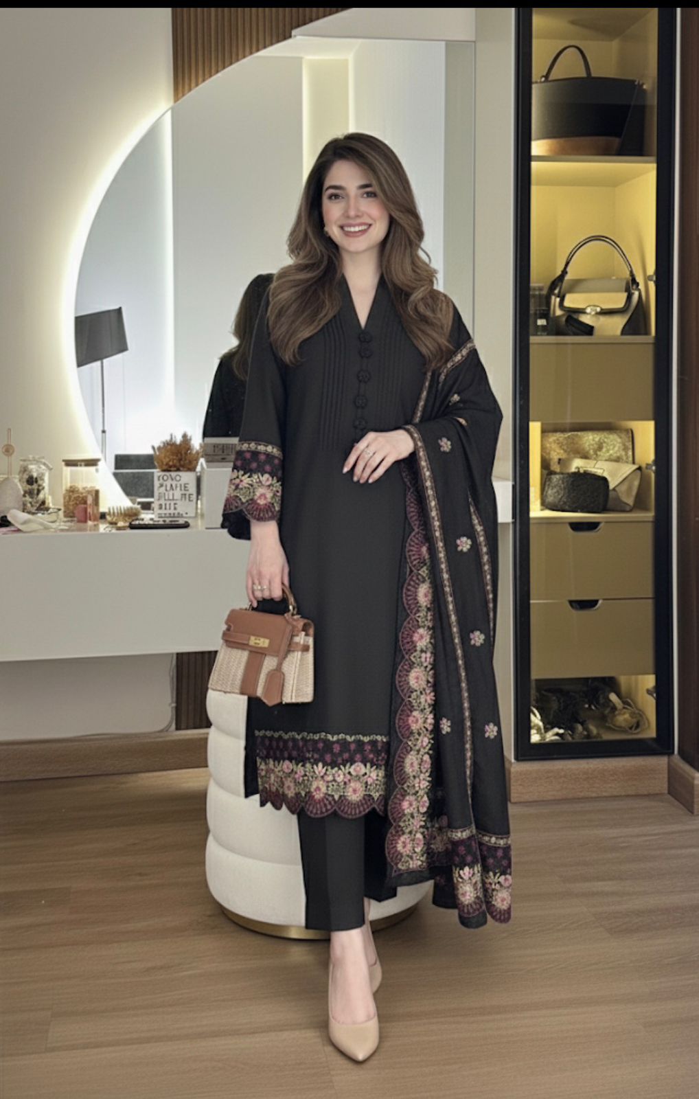 Woman in a black outfit with floral patterns standing in a room with shelves and decor.