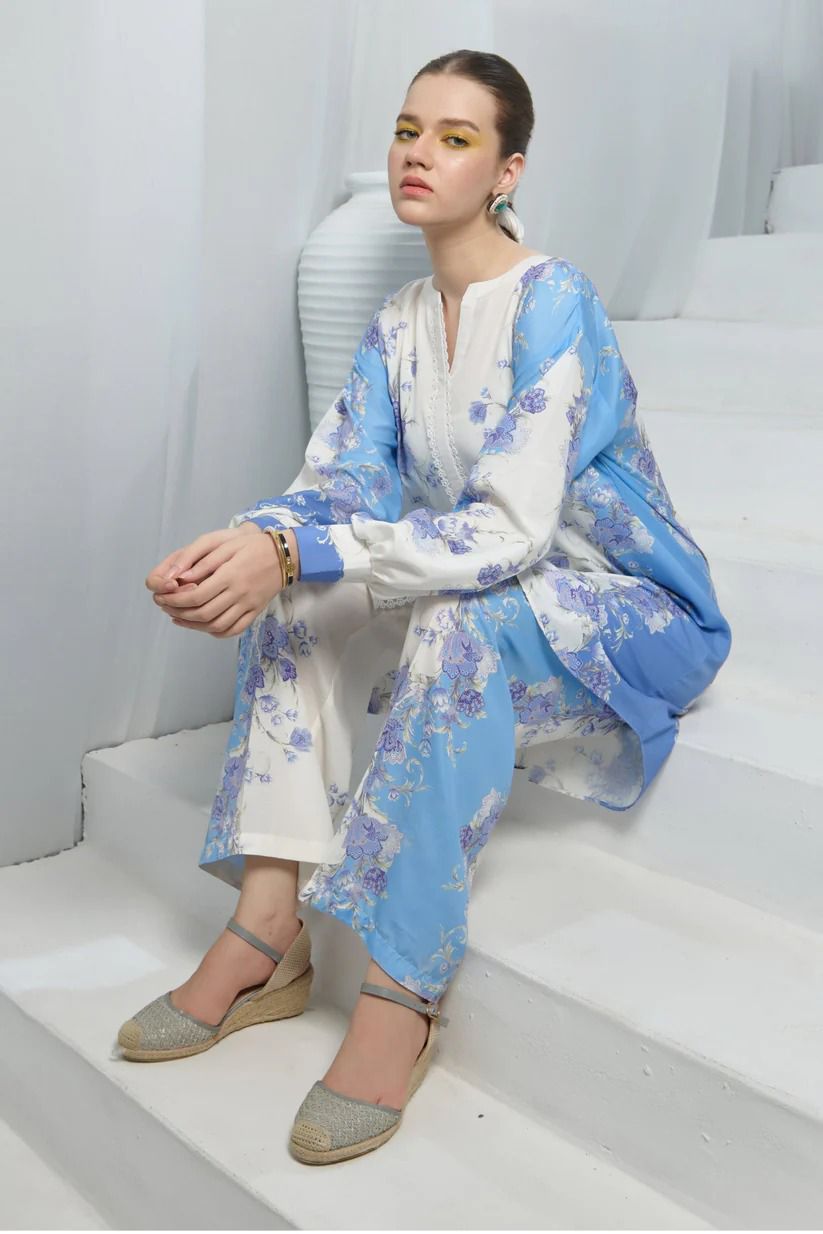 Woman sitting on stairs wearing a blue and white floral outfit with a white background