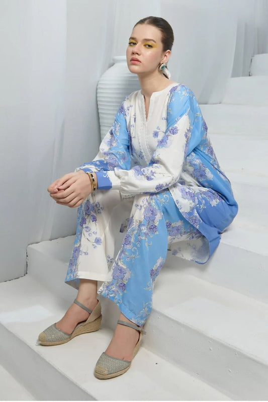 Woman sitting on stairs wearing a blue and white floral outfit with a white background