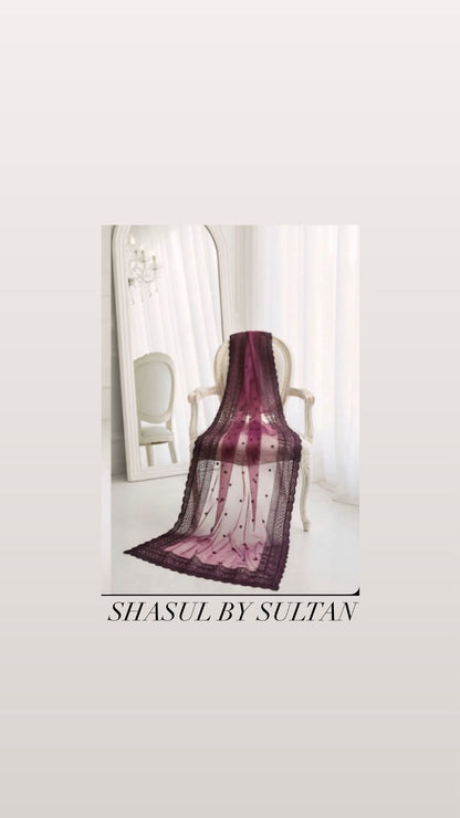 Purple lace shawl draped over a chair with 'Shasul by Sultan' branding.