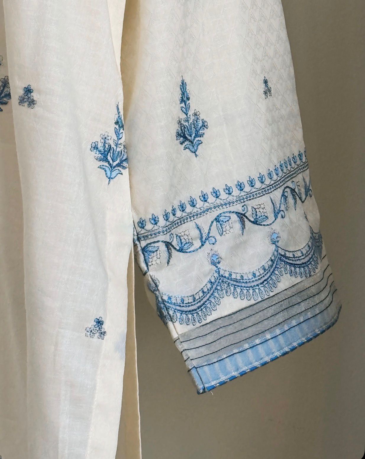 White fabric with blue embroidery on a beige background