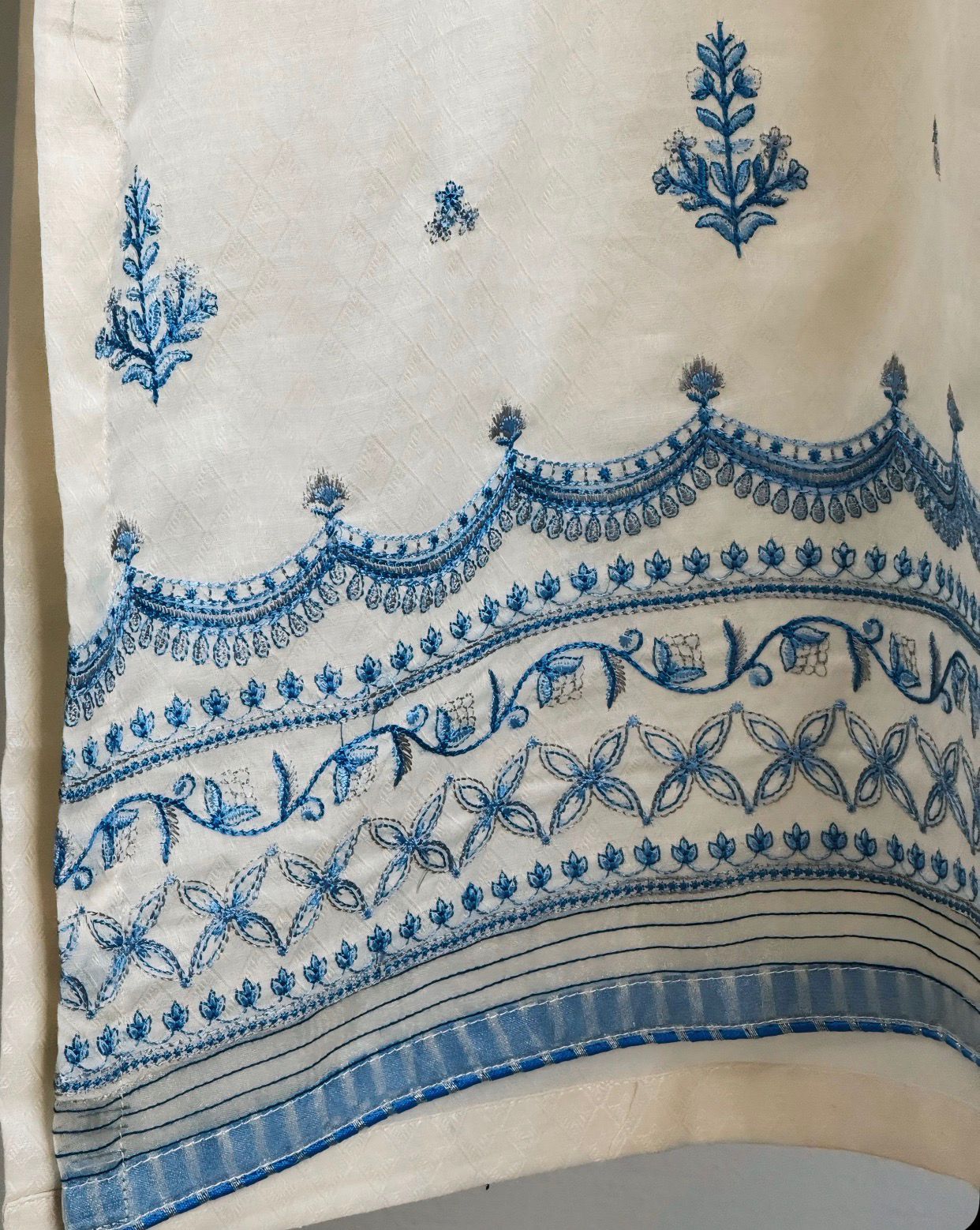 Embroidered fabric with blue floral and geometric patterns on a beige background