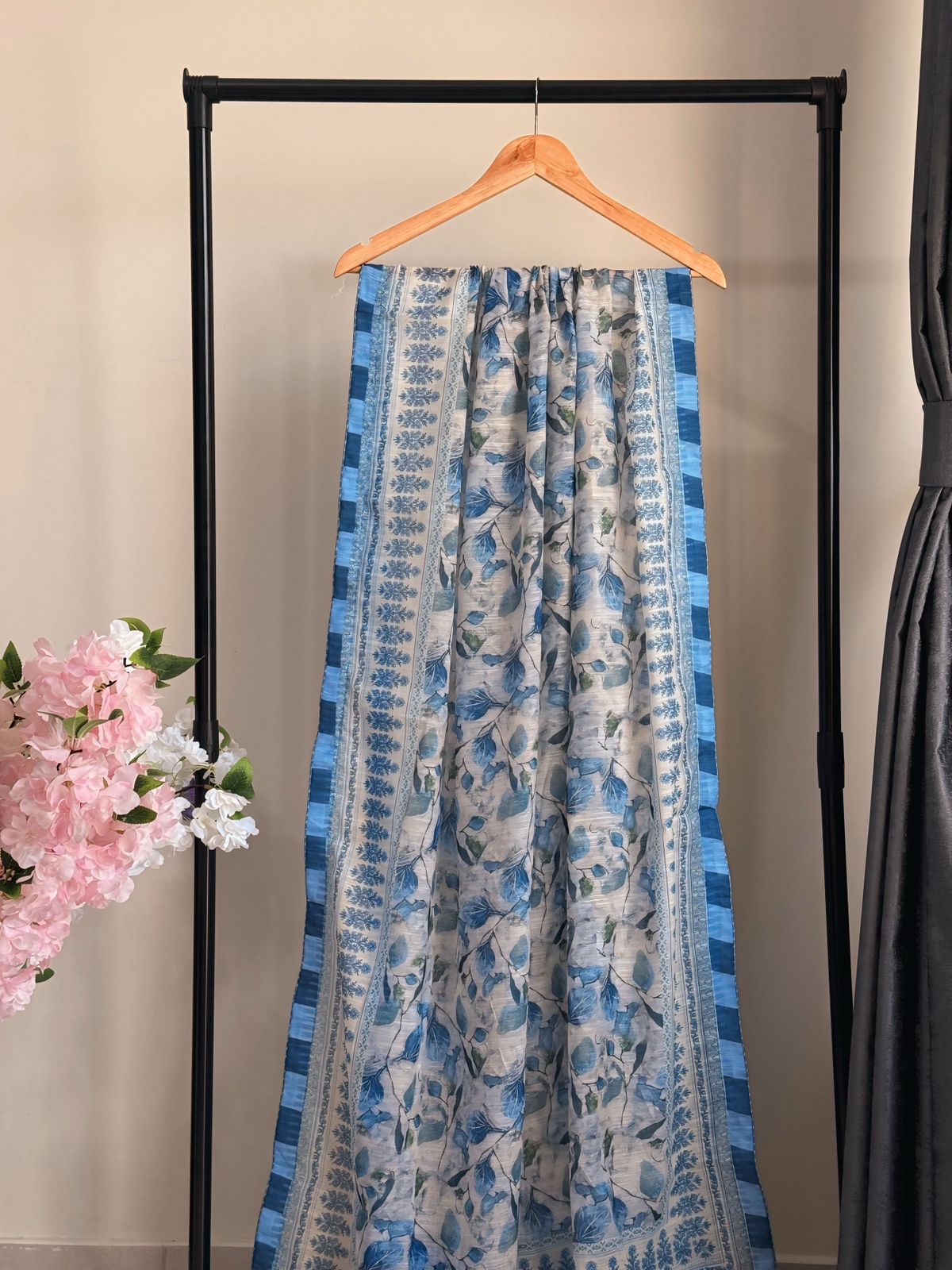 Blue and white patterned skirt hanging on a rack with flowers in the background