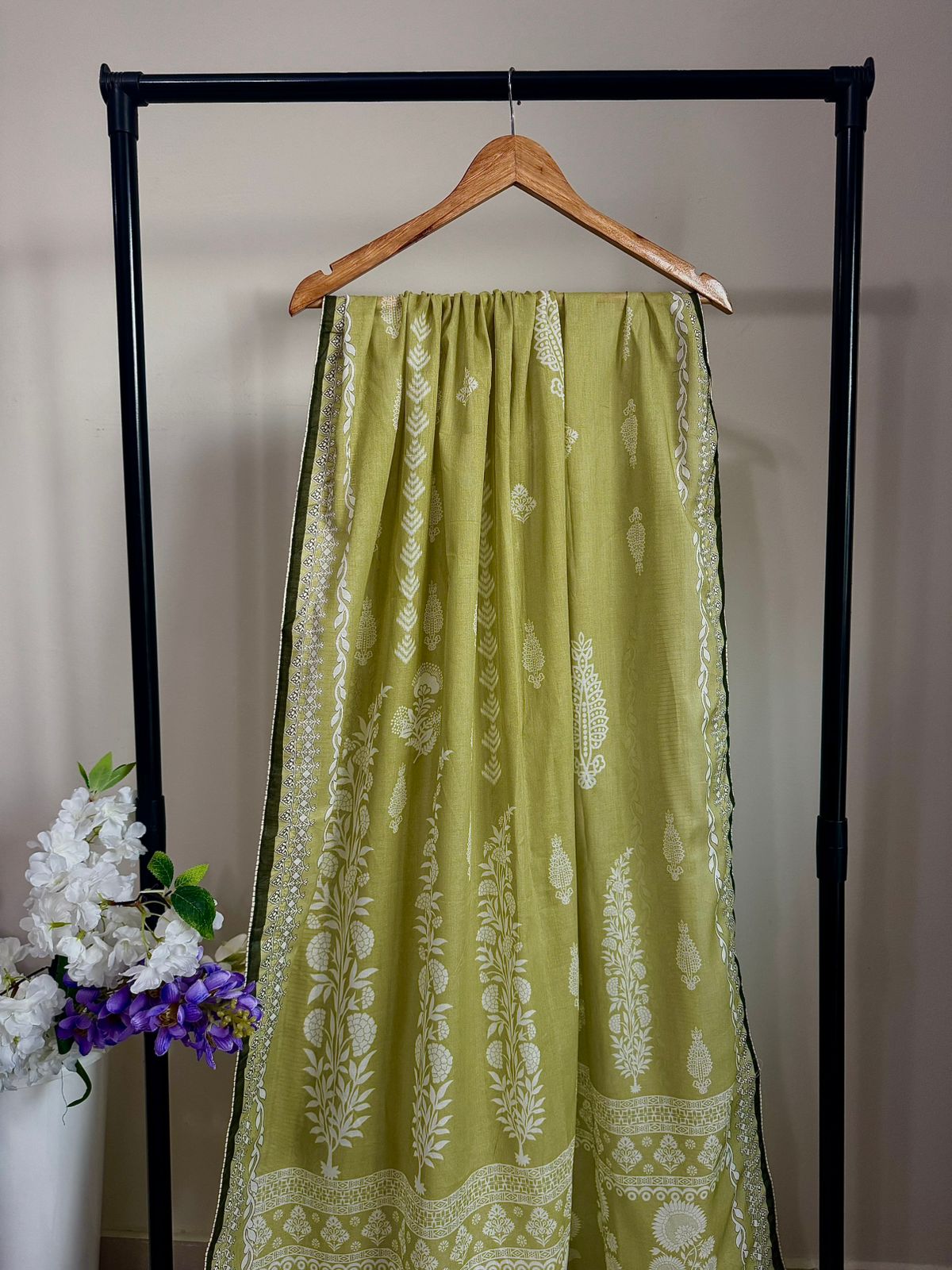 Green patterned skirt on a hanger against a neutral background