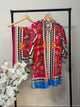 Colorful embroidered shirts on a rack with white flowers in the foreground
